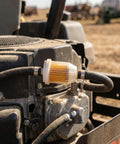 Fuel Filter 1/4 Inch And 5/16 Inch Two Pack Plug And Play Replacement mounted on a lawn mower engine, blocking debris.