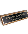 Personalized Walnut Wood Desk Name Plate With Black Base And Gold Lettering, 2 By 8 Inches on desk displaying 'Robert Johnson'