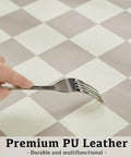 Close-up of fork testing durability on Large Checkered Desk Pad 31.5 Inch By 15.7 Inch Premium PU Leather Desk Mat Waterproof Surface