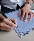 Person writing on Vintage Airmail Themed Stationery Set With 100 Pieces Letter Size 8.5 By 11 Inches Including 50 Lined Sheets