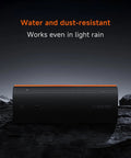 Boom Out Loud Party Bluetooth Speaker 50W Power, Waterproof Portable Wireless Audio, 26 Hour Playtime For Outdoor Ragers Sync Up To 100 Units Super Cool Design on a rocky surface with water droplets.