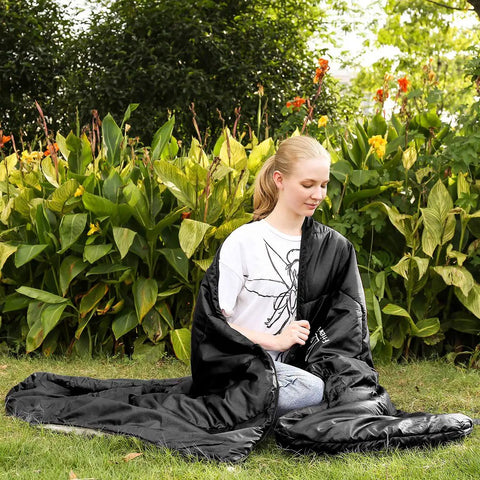 Person sitting outside wrapped in XL Widened Upgraded 4 Season Camping Sleeping Bag For Adults And Kids Built Tough Waterproof Lightweight 0F Warmth