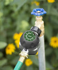 High Flow Metal Watering Timer With Twenty Percent More Water Flow Than Standard Timers attached to outdoor faucet with flowers