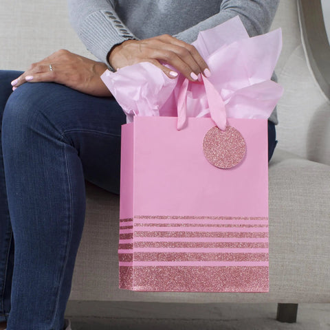 Person holding 9-Inch Medium Gift Bag With Tissue Paper In Pink Glitter Stripes For Valentines Day Birthdays Baby Showers Bridal Showers Or Any Occasion Durable Gift Bag With Card Holder And Up To Five-Pound Capacity