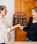Two women holding a Wooden Squirrel Picnic Table Feeder With Multi Compart ment Seed Storage And Five Level Bar Stools