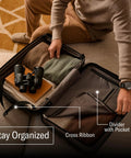 Person organizing Samsonite hard shell carry-on luggage with cross ribbons and dividers.