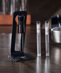 Hella Smooth Breville Espresso Accessories Kit With Bottomless Portafilter Plus Spring Loaded Tamper Featuring Rosewood Knock Box And Wdt Needle Distribution Station with WDT needle holder and measuring needles on a wooden table.