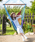Woman relaxing in Upgraded Caribbean Hammock Chair With Detachable Steel Bar Large XL Rope Hanging Swing Chair for outdoor use.