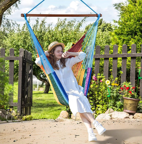 Woman relaxing in Upgraded Caribbean Hammock Chair With Detachable Steel Bar Large XL Rope Hanging Swing Chair for outdoor use.