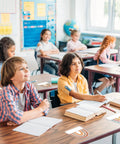 Students in a classroom with Rainbow Cutouts For Classroom Decor, 45 Pcs Boho Rainbow Name Tags With 100 Glue Dots on desks