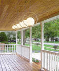 Plug In Globe Pendant Light Fixture With White Glass Ball And Brushed Brass Ring hanging on porch ceiling