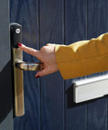 Person using No Sweat Smart Keyless Front Door Handle With Polished Brass Finish and Smartphone App Control.