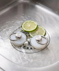 White Drain Stopper with Stainless Steel Ring, Silicone Seal Plug in stainless sink with sliced limes.