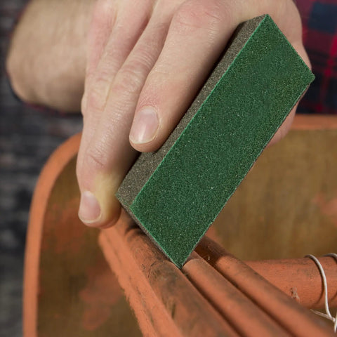 Hand using Medium 80 Grit Dual Angle Sanding Sponge 3x5x1 Inch for wet or dry use on wooden surface, flexible handheld pad with grit on all sides.