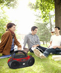 Portable Top-Loading CD Boombox With AM/FM Radio and 3.5mm Line In, red and black, in park setting with group of people outdoors