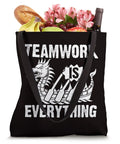 Black tote bag with 'Teamwork Is Everything' text and dragon graphic, filled with groceries. Teamwork Is Everything Tote Bag For Paddling Crew Fans Race Day Gear And Training Sessions Big Enough For Gear And Water Vibe Print Tough Canvas Tote For Adrenaline Fueled Practices And Weekend Meetups.
