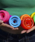 Person holding multi-colored Zen Quad Roller Skate Wheels 4 Pack 32mm x 62mm 85A Durable Urethane Black For Rink Street And Sidewalk Use