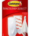 Medium White Spring Clip With Three Strips For Damage Free Hanging in packaging, Command brand on red background.