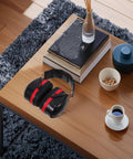Black and red double layer over ear earmuffs on a wooden table, designed for construction mowing and shop jobs.
