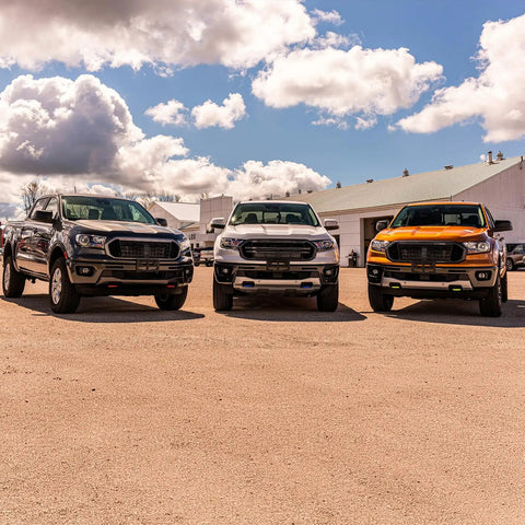 Three trucks equipped with Red Tow Hook Covers For Ford F-150 2004-2024 And Toyota Tundra 2017-2021 in a sunny outdoor setting.