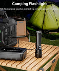 Ridiculously Bright 20000 Lumen USB Rechargeable LED Flashlight, 30W Output beside power bank on outdoor table with tent in background.