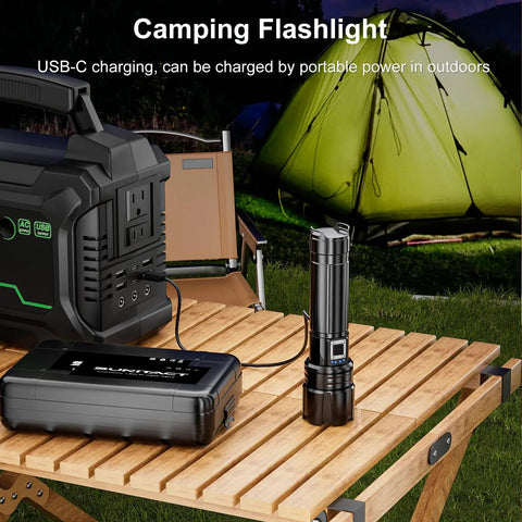 Ridiculously Bright 20000 Lumen USB Rechargeable LED Flashlight, 30W Output beside power bank on outdoor table with tent in background.