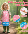Pink Kids Gardening Tools Set With Rake Shovel Trowel Watering Can Gloves Apron Tote Bag Plant Pots And DIY Bookmark Kits For Toddlers, child in garden apron with pockets standing outdoors