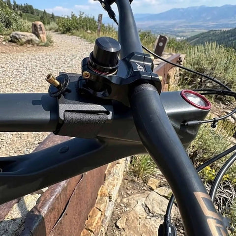 Hands Free Bar Stem Dock For Bike Repair With Foam Pad And Strap shown securing handlebars on mountain terrain