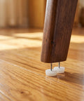 Wooden chair leg on hardwood floor with white round chair glides for hardwood floors and carpet, 100 pack of plastic and metal furniture leg protectors