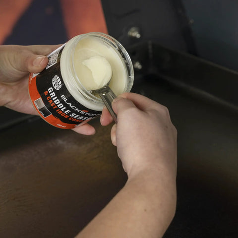 Hands holding Griddle Seasoning And Cast Iron Conditioner 2 In 1 Formula For Nonstick Release And Rust Protection 15.3oz Bottle