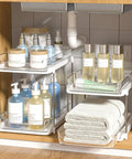Super Handy Two Tier Under Sink Organizers And Bathroom Storage Solutions For Cabinets And Kitchen Pantries With Smooth Slide Out Drawers And Fully Adjustable Dividers In Bright White Two Pack filled with toiletries.