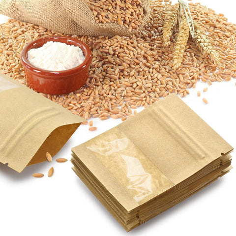 Stack of 100 Pack Resealable Mini Kraft Bags With Window For Samples next to wheat grains and flour