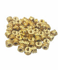 Pile of M3 0.5 threaded heat set inserts for 3D printing, brass material, showcasing tapered design and finned ridges for strong threads.