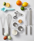 Top view of kitchen tools including Stainless Steel Measuring Cup Set Four Piece For Baking And Cooking surrounded by ingredients.