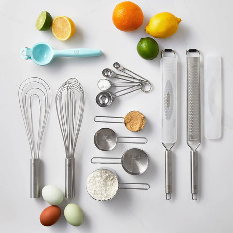 Top view of kitchen tools including Stainless Steel Measuring Cup Set Four Piece For Baking And Cooking surrounded by ingredients.