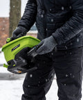 Person using 20-Volt Cordless Handheld Seed And Fertilizer Spreader For Yard Work With Adjustable Spreading Rate Dial in snow