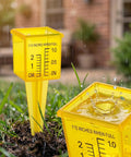 Four Pack Outdoor Rain Gauge With Wide Mouth 1.5 Inch Markings Ground Stake Yard Garden Sprinkler Irrigation Tool Easy Rainfall Readout For Lawn Care Pros High Visibility Yellow Weather Instrument in grass