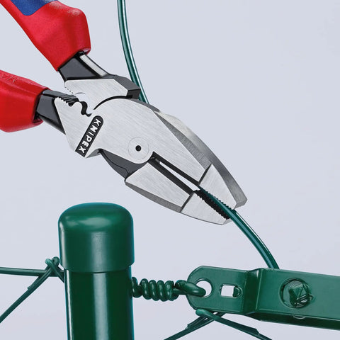 Ultra-High Leverage 9 1/4 Inch Lineman Pliers With Fish Tape Puller And Crimper cutting wire on a green fence post.