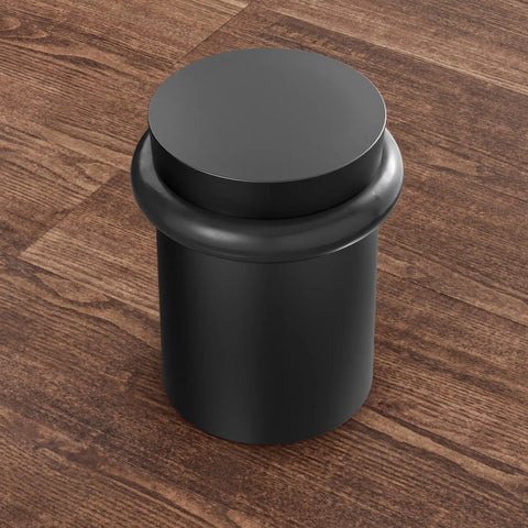 Heavy Duty Solid Steel Floor Door Stopper Matte Black Wall Protector Rubber Bumper on wooden floor, cylindrical design, top view.