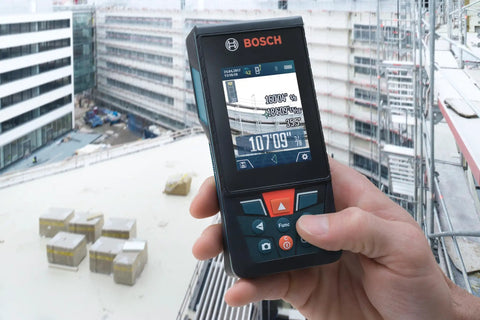 Hand holding Beast Of A Blaze Outdoor Connected Laser Measure With 400 Ft Range, 5 MP Digital Viewfinder at construction site