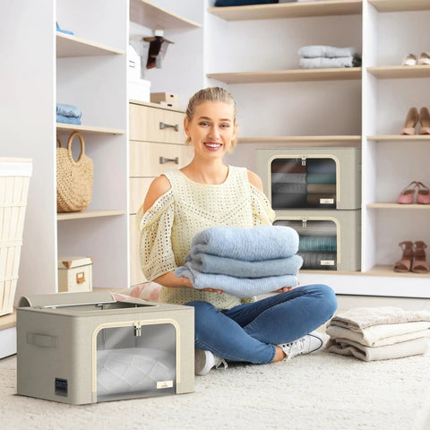 Person holding folded clothes with beige stackable storage bins with metal frame for closet organization in the background.
