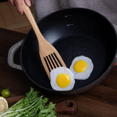 Cooking eggs in a pan with Three Piece Acacia Wood Spatula Set For Cooking, Teethed Pasta Spoon And Spaghetti Fork.