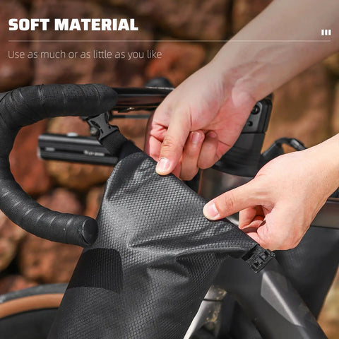 Hands securing a 5L Waterproof Bike Fork Bag For Mountain And Road Bikes Front Pannier Dry Bag with roll top closure on handlebars.