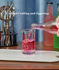 Pouring liquid into Glass Shot Measuring Cup 4oz for Cocktails and Espresso with Bar Grade Multi Scale Markings in Ounces Milliliters And Cups Red Line for Home Mixologists