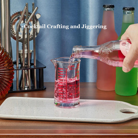 Pouring liquid into Glass Shot Measuring Cup 4oz for Cocktails and Espresso with Bar Grade Multi Scale Markings in Ounces Milliliters And Cups Red Line for Home Mixologists