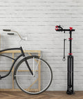Bike Repair Stand Height Adjustable Work Station With 360 Degree Rotating Clamp And Quick Release Mechanism next to a bicycle