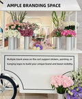 Slick Portable Vendor Cart With Heavy Duty Rubber Wheels And Locking Storage Cabinet For Farmers Markets Pop Up Booths And Flower Display Racks That Keep Your Street Hustle Going Strong showcasing flowers, ample branding space, and solid wheels.