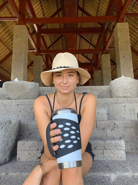 Person holding 20 oz stainless steel vacuum insulated mug with protective silicone tumbler sleeve with handle and comfy grip.