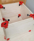 4 Pack Right Angle Corner Clamps For Cabinet Making And Box Assembly securing a wooden box at a 90 degree angle on a table