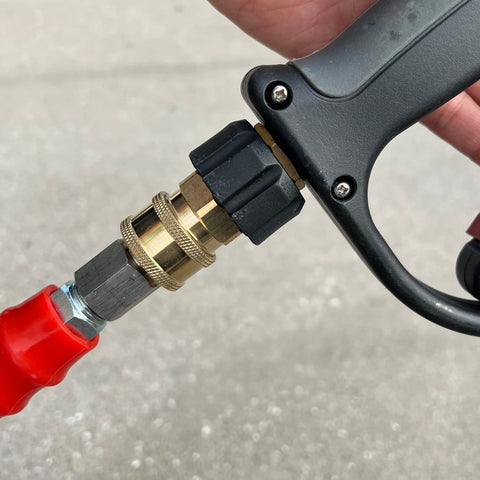 Close-up of brass M22 14mm to 3/8 in quick-connect pressure washer coupler attached to a black spray gun handle